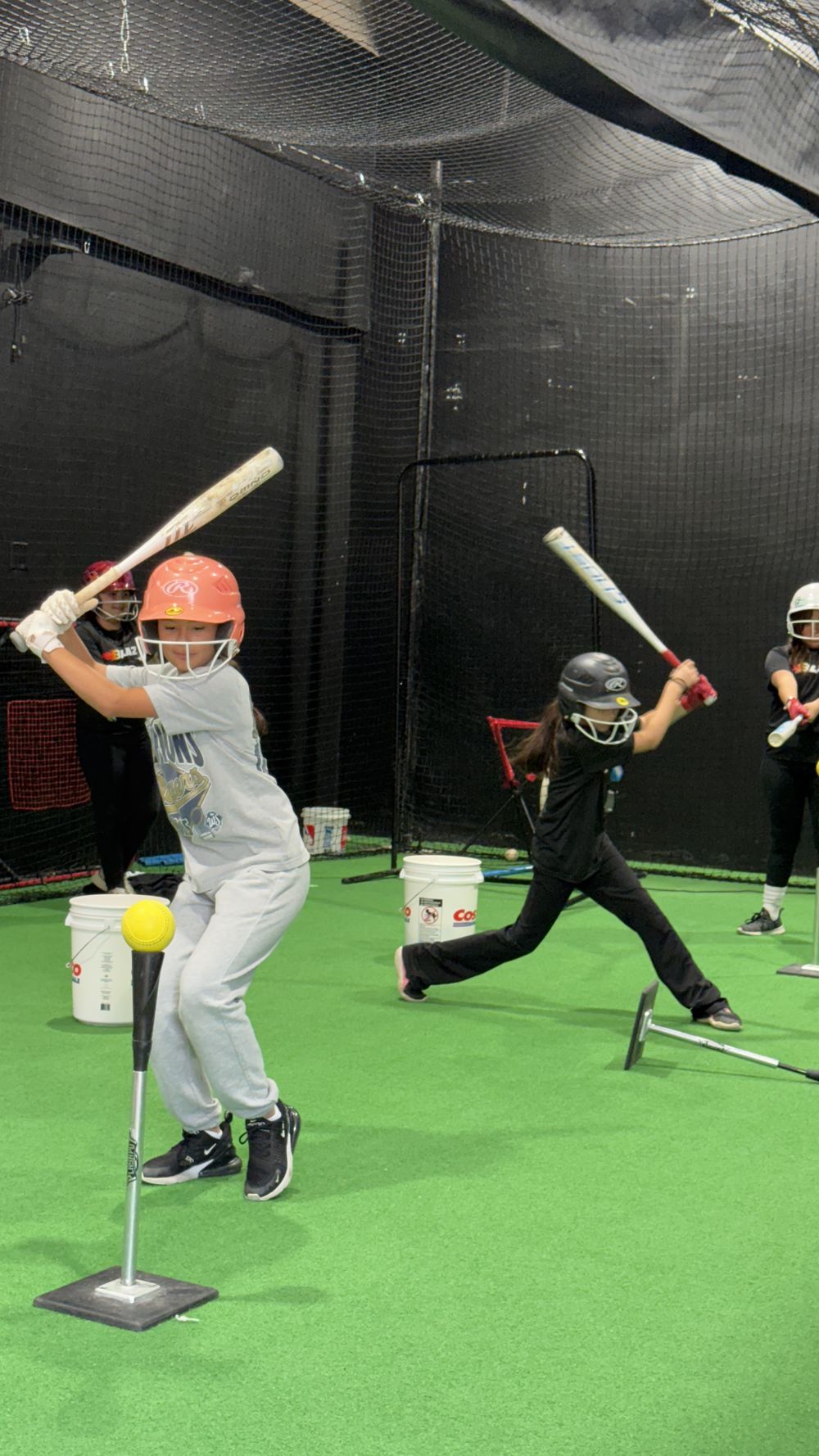 Young players hitting off tees in the cages at Launchpad Baseball Academy